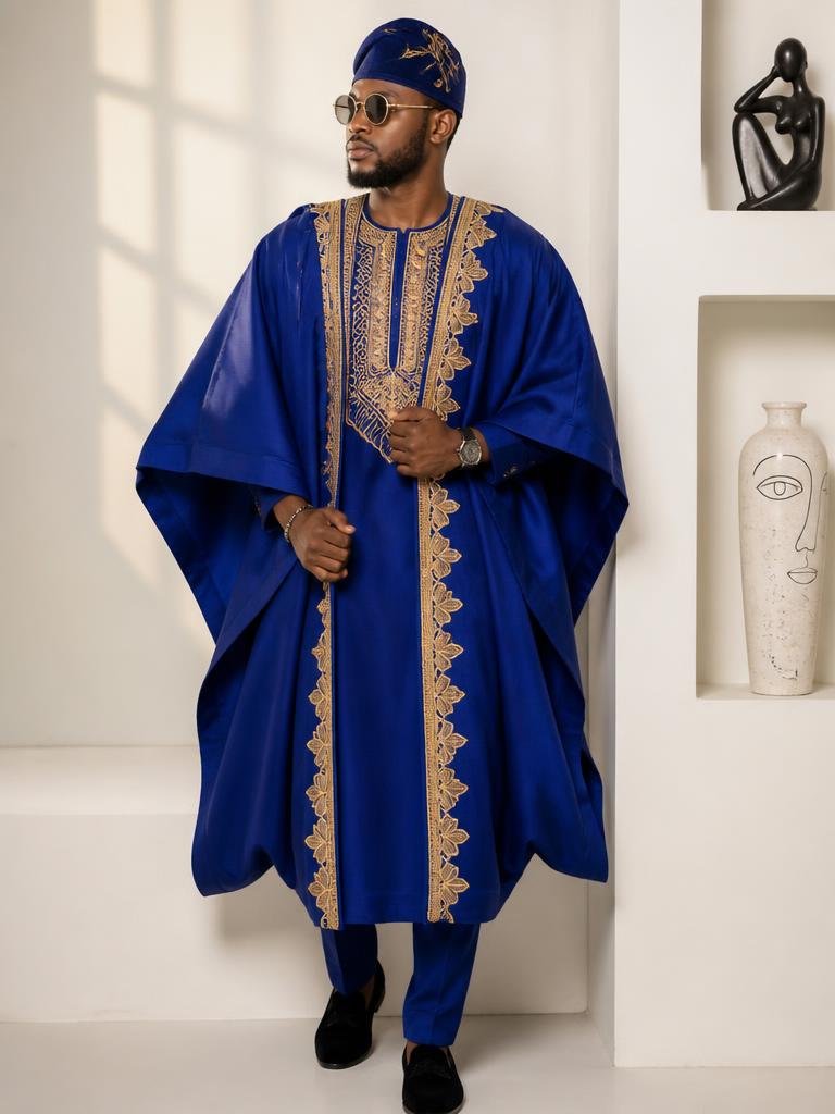 Man in a royal blue agbada with gold embroidery in a bright studio